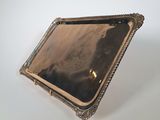 an antique silver tray with a mirror on it on a white surface