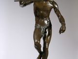 bronze statue of a man holding a sword on a wooden base