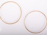two pairs of gold hoop earrings on a white surface