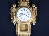 une horloge dorée accrochée au mur, sur fond noir