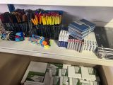 many pens and pencils sitting on a shelf in a room