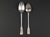 two silver spoons on a black surface with a black background
