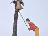 a figurine of a man holding a bell on a pole