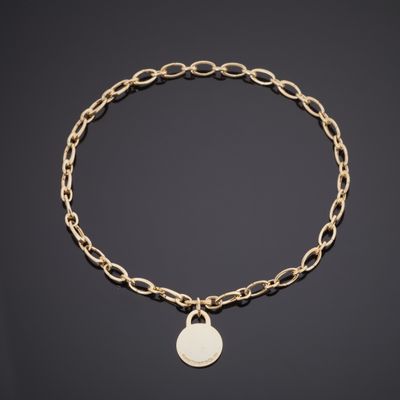 un bracelet en chaîne d'or orné d'une breloque en forme de pièce de monnaie