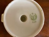 a white bowl with a green design on it on a wooden table