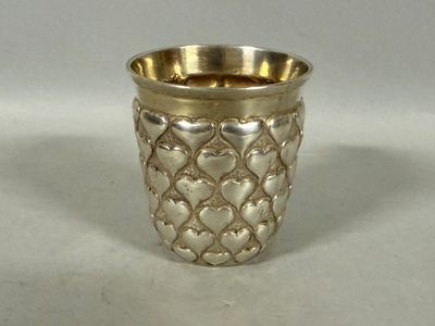 une coupe en argent ornée de cœurs sur un fond blanc