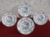 trois assiettes ornées de fleurs, posées sur une nappe rouge