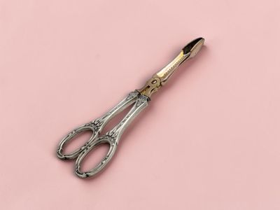 une paire de ciseaux posée sur une surface rose