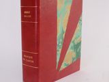 an old red book with a yellow and green cover on a white surface