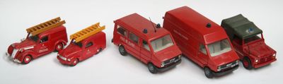 quatre camions miniatures alignés sur une surface blanche