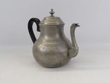 an antique silver teapot with a black handle on a white surface