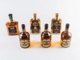 six bottles of whiskey lined up in a row on a white surface