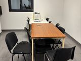 une longue table avec des chaises et un ordinateur portable posé dessus, dans une pièce