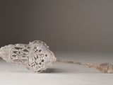 a silver spoon with a handle on a white surface