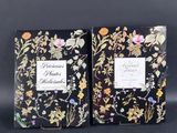 a pair of black books with floral designs on them