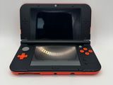une Nintendo 3DS orange et noire posée sur une table blanche