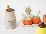 a little girl sitting on a plate next to a jar of pumpkins