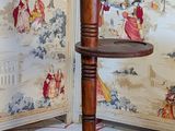 a wooden table with a shelf on it in front of a wallpapered room