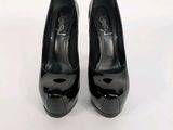 des chaussures à talons hauts noires posées sur une surface blanche, avec un fond blanc