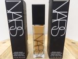 two bottles of nars cosmetics sitting on top of a wooden table