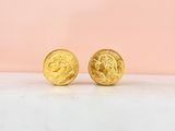 a close up of a pair of gold earrings on a marble surface