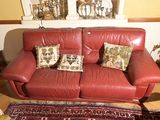 un canapé en cuir rouge avec deux coussins et un tapis au sol