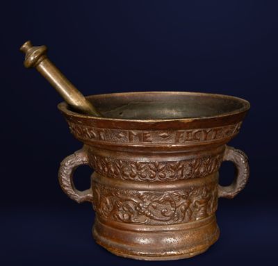 mortier et pilon en bronze sur fond sombre, avec un fond bleu
