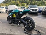 a green motorcycle parked in a parking lot with other cars