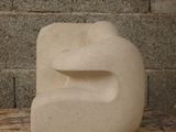 a white sculpture on a wooden table in front of a brick wall