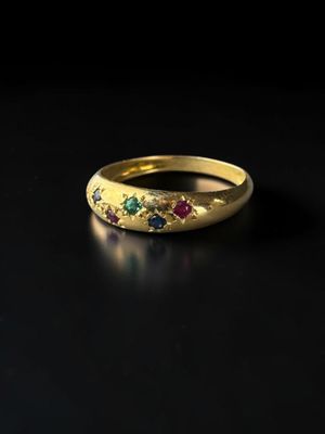 gros plan d'une bague en or avec des pierres multicolores