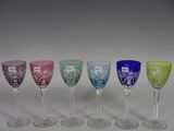 several different colored wine glasses are lined up on a white surface