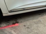 a white car with a red light on the side of the road