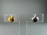 a pair of earrings that are sitting on a clear stand