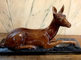 statue d'un cerf couché sur un socle noir posé sur une table en bois