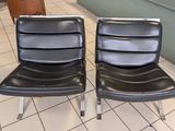 pair of black leather chairs sitting on a tiled floor in a room