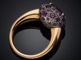 a close up of a gold ring with a purple stone