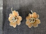 une paire de boucles d'oreilles en forme de fleurs jaunes posées sur un tissu bleu