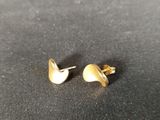 a close up of a pair of gold earrings on a black surface