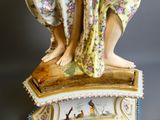 une figurine représentant une femme tenant un oiseau sur un socle