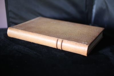 un livre en cuir marron posé sur un canapé noir