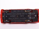 underside view of a red and black electronic device on a white surface