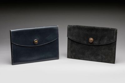 two black and brown leather wallets sitting side by side