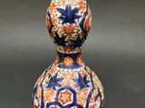 an orange and blue gourd shaped vase sitting on top of a table