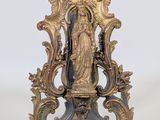 une statue représentant une femme, posée sur un socle, sur une surface blanche