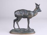 bronze statue of a gazelle standing on a base on a white background