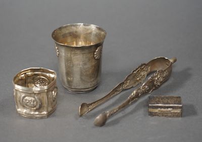 une tasse en argent, une cuillère et un repose-cuillère posés sur une table