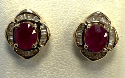 deux paires de boucles d'oreilles en rubis et diamants posées sur un fond blanc