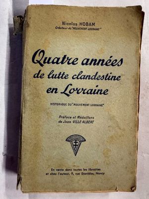 un vieux livre posé sur une table à côté d'un mur blanc