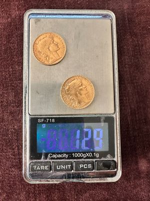 une petite balance sur laquelle repose une pièce de monnaie et une calculatrice posée sur la table