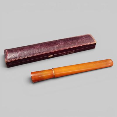 deux stylos en bois et un étui en cuir posés sur une surface grise